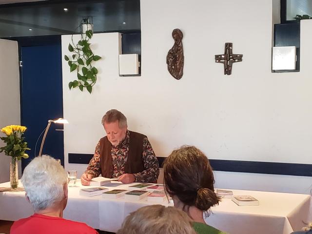 Herbert Dutzler liest aus einem seiner Bücher, die am Tisch vor ihm ausgebreitet sind